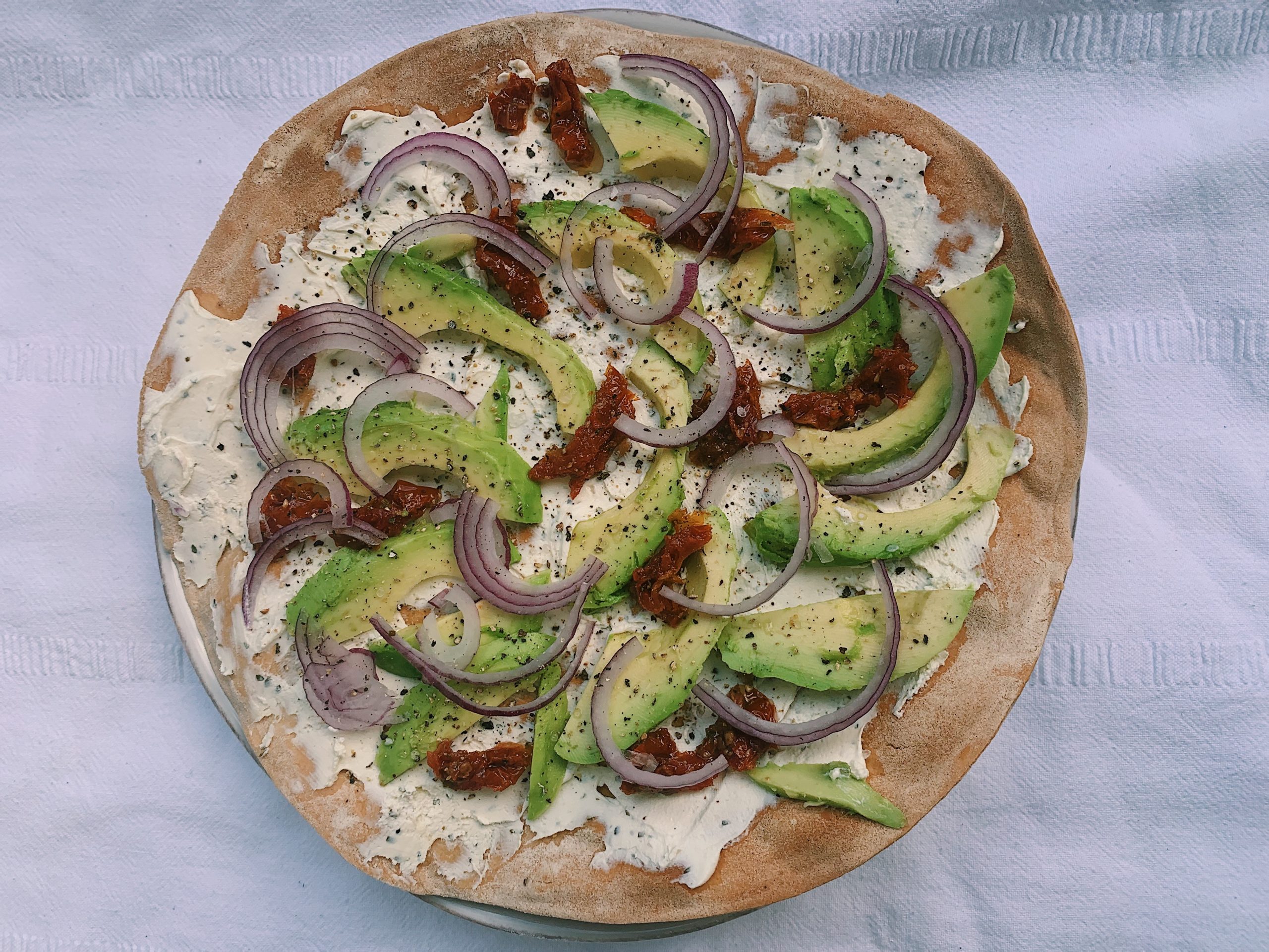 Flammkuchen met avocado, ui en zongedroogde tomaten